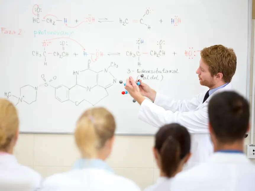 Science teacher demonstrating molecular model in front of whiteboard