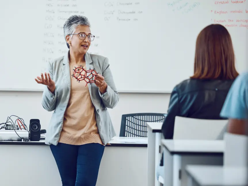 Female teacher explaining a STEM concept to older pupils using a molecular model