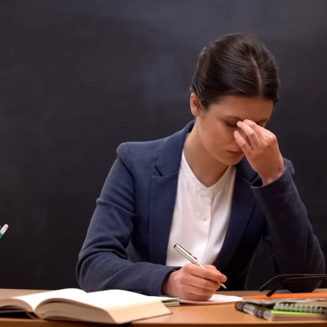 A school leader sitting at a desk looking thoughtful and tired, reflecting on workload and time management. Text overlay reads “Time, Priorities & Focus Toolkit.
