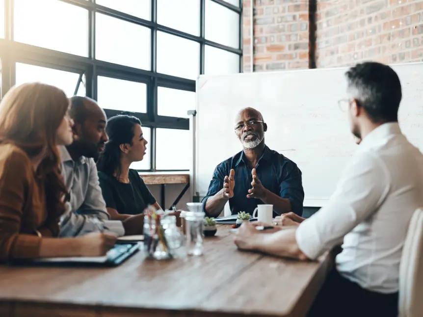 Senior leadership team in strategic discussion designing sustainable systems before pressure escalates.